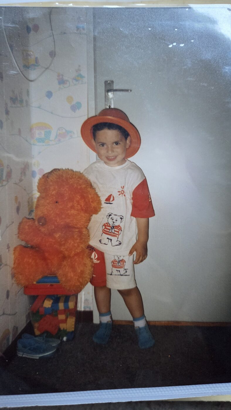 Young Mustafa with orange hat and teddy bear