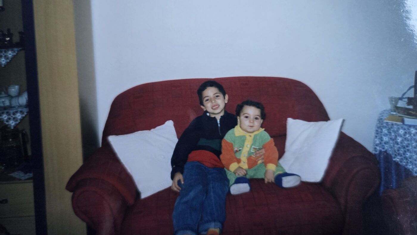 Jonge Mustafa houdt baby Abdullah vast op een rode bank